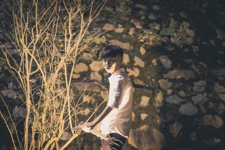 a boy holding a paddle next to a plant and trees