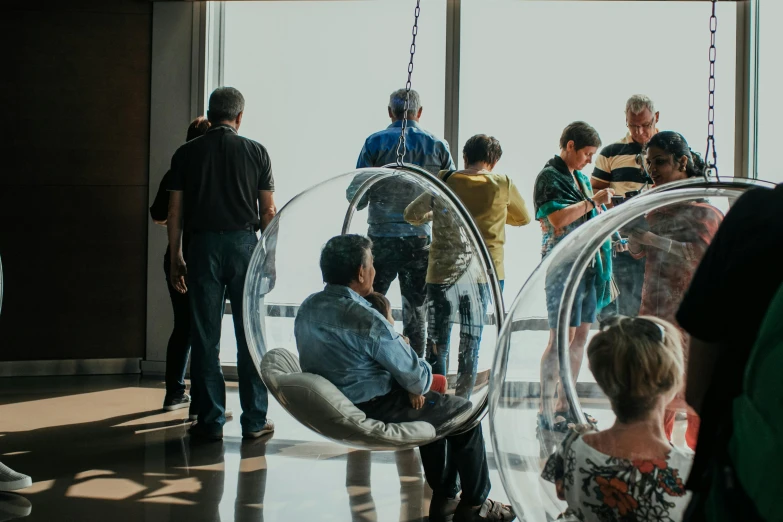 some people standing around a glass wall and in swings