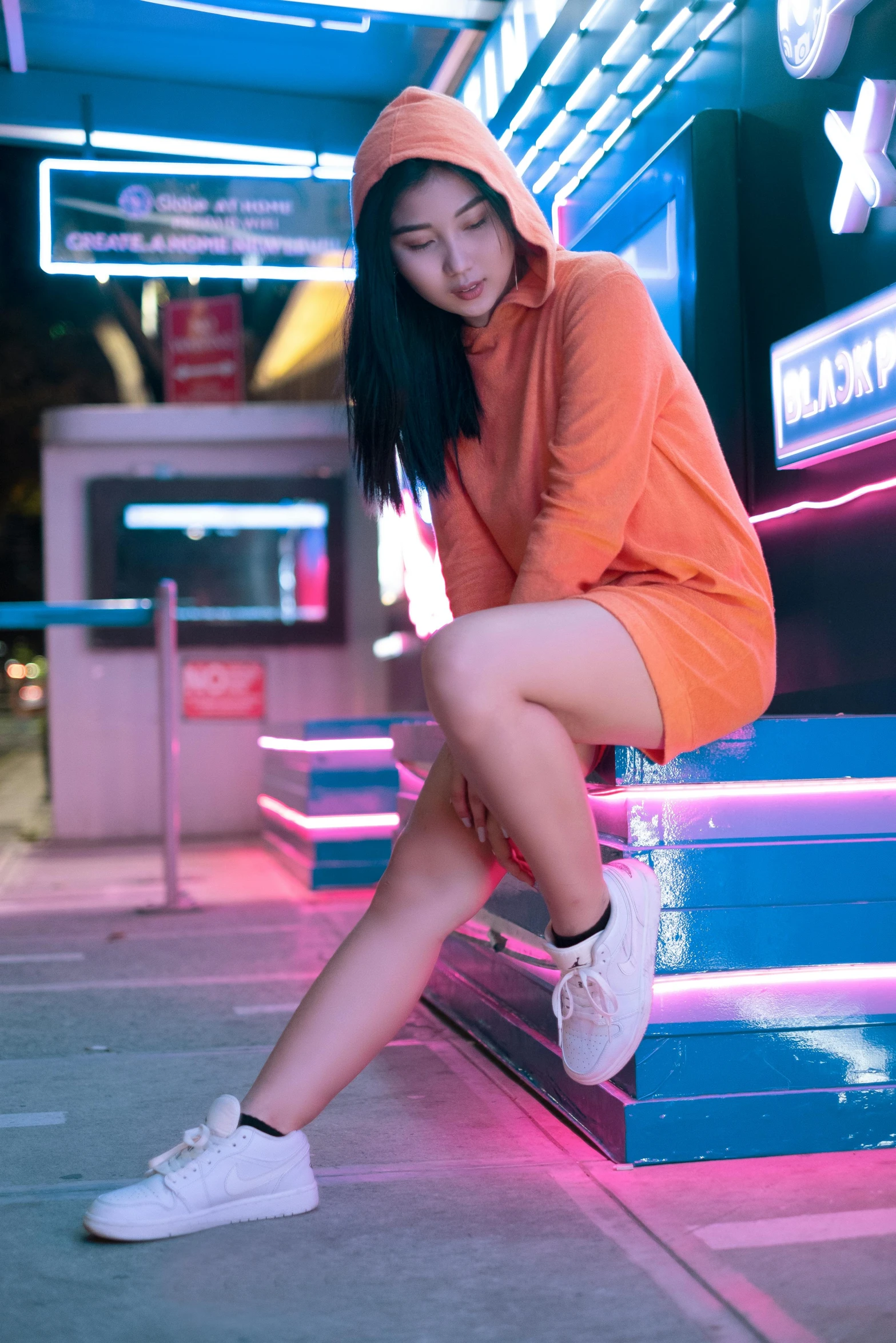 a beautiful young woman in an orange hoodie sitting on stairs