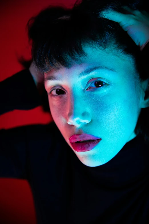 a woman's face glowing with blue and pink light