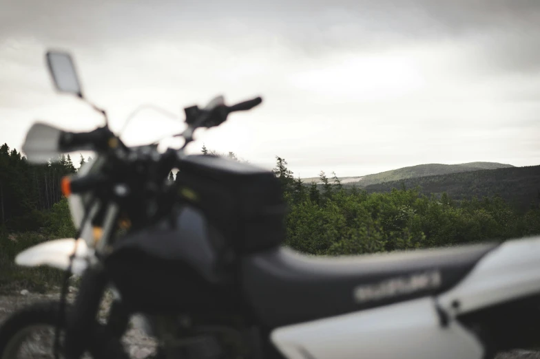 a motorcycle parked in a gravel lot in the woods