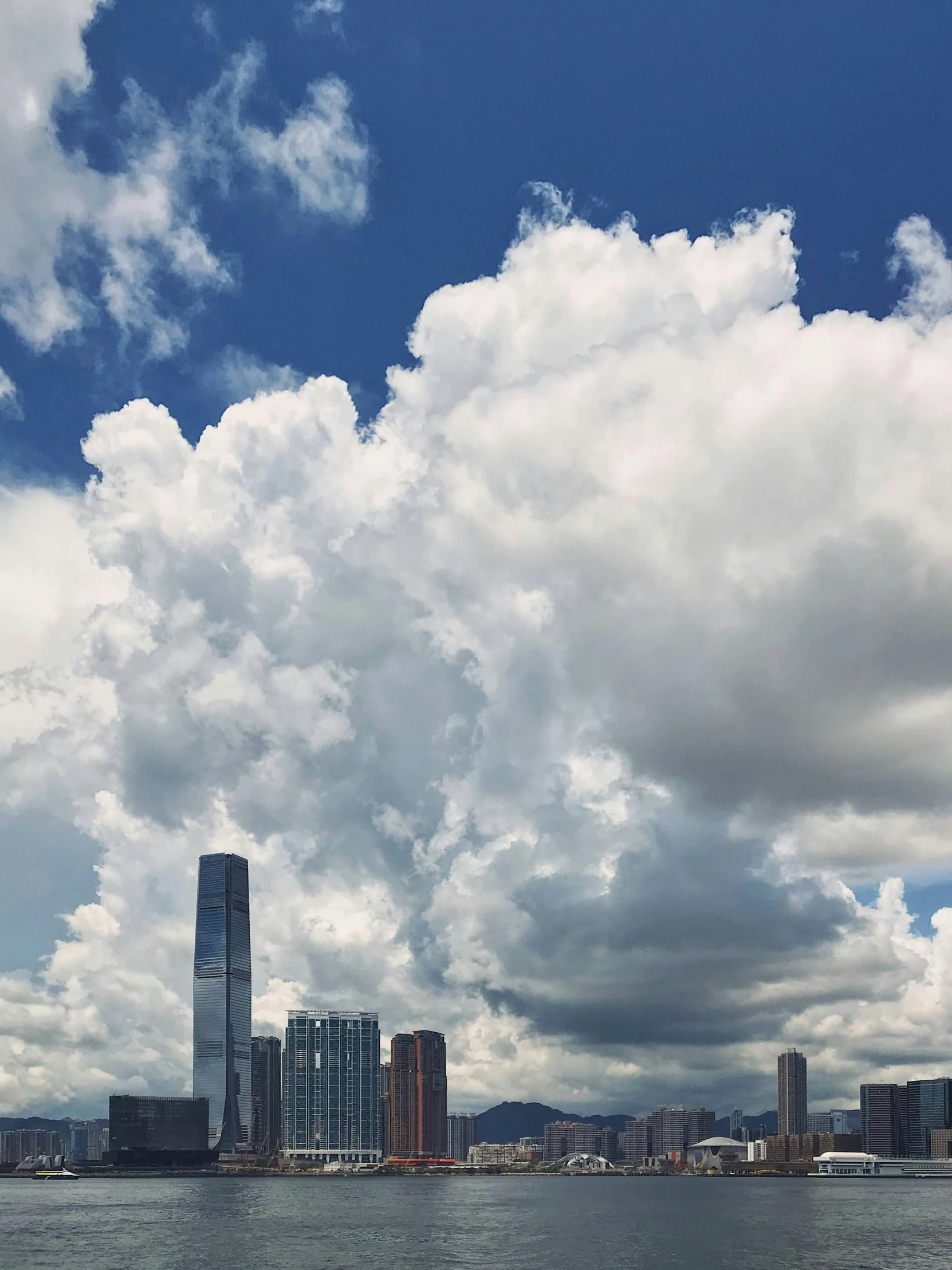 a view of the clouds from the water in the middle of a city