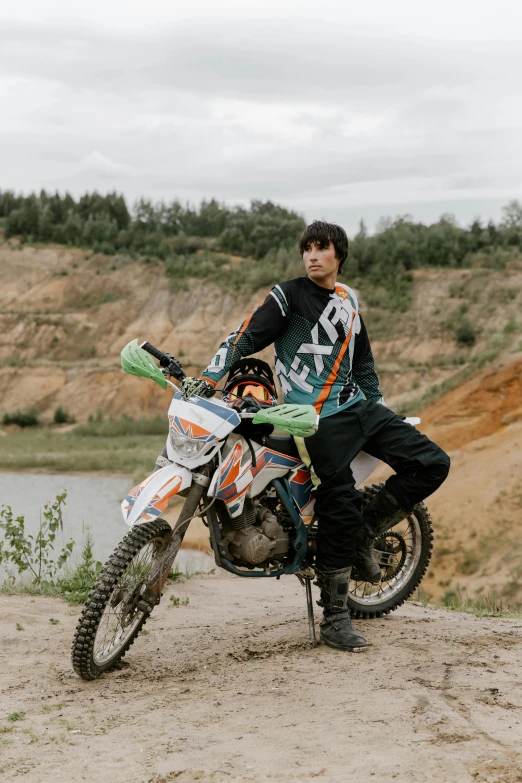 a man riding a motorcycle on a dirt road near a river