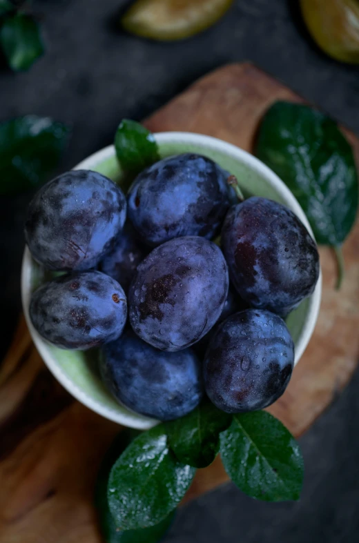 a small white bowl with plums in it