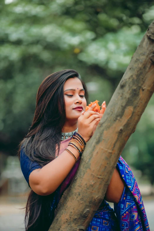 a woman holding onto the tree nch while eating soing