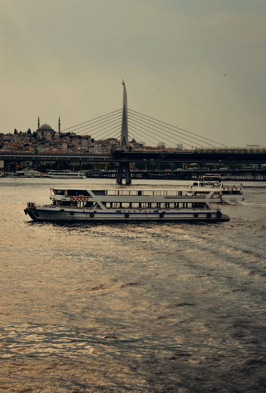 three ferryboats on the water near a bridge