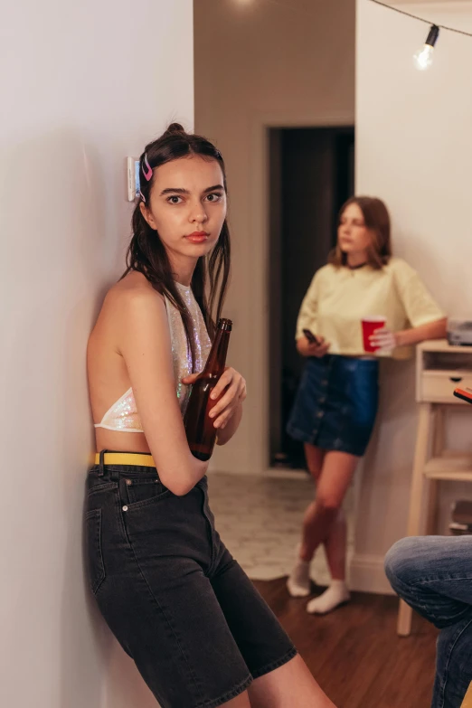 woman in yellow shirt leaning against wall near two girls