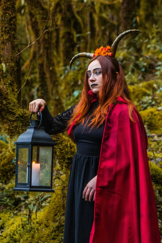 a woman in a red cape is holding a lantern