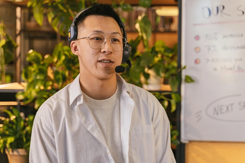 a man wearing glasses and holding a headset up