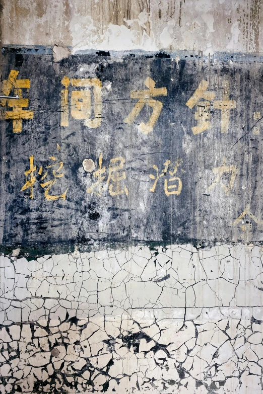 a sign in different languages, painted on the outside of an old wall