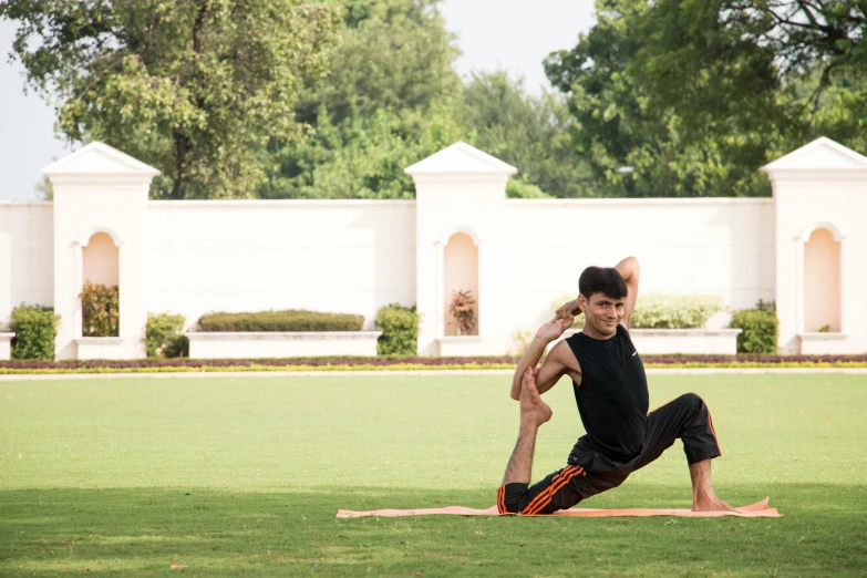 a man stretching in the park on his yoga mat
