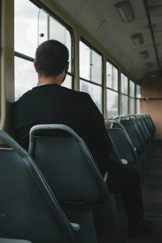 the man sitting on the bus looks out the window