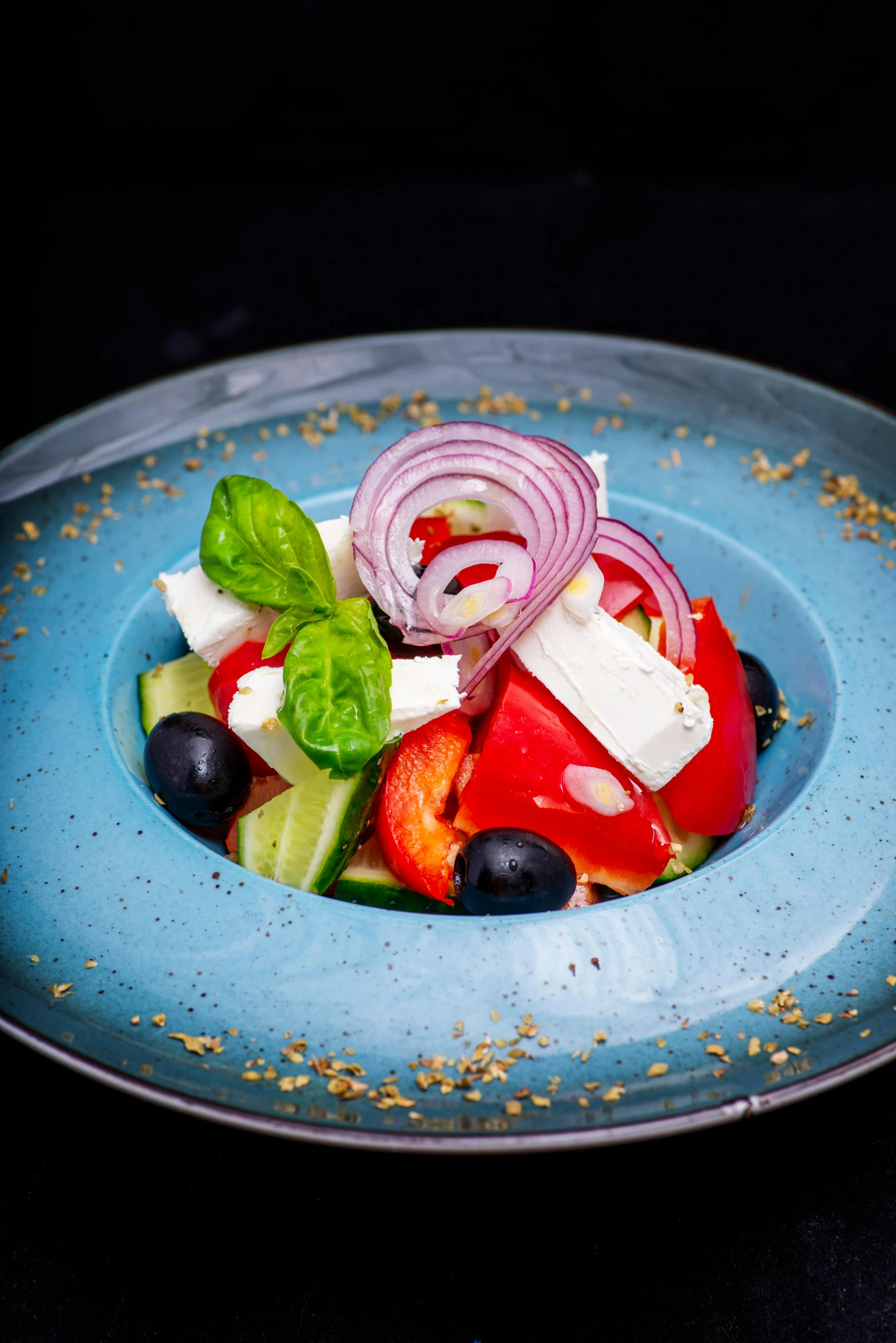 a colorful salad that has tomatoes, blueberries, onion and cheese on it