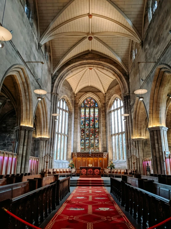 a red carpet is in between pews and large windows