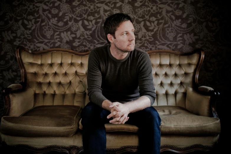 a man sitting on top of an old style couch