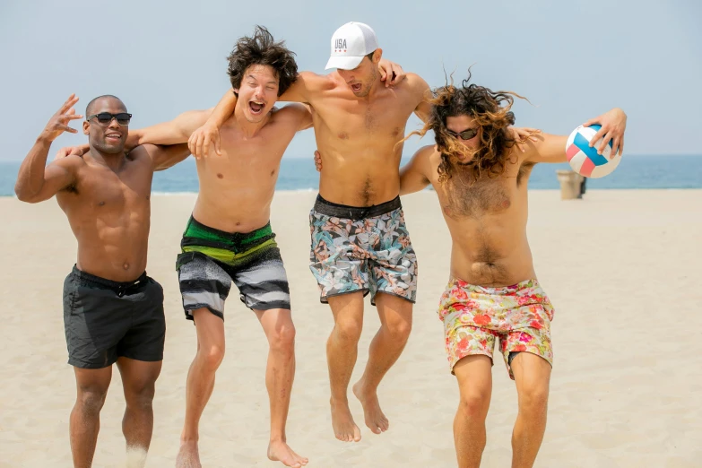 three guys having fun at the beach with one jumping and holding the ball in his hands