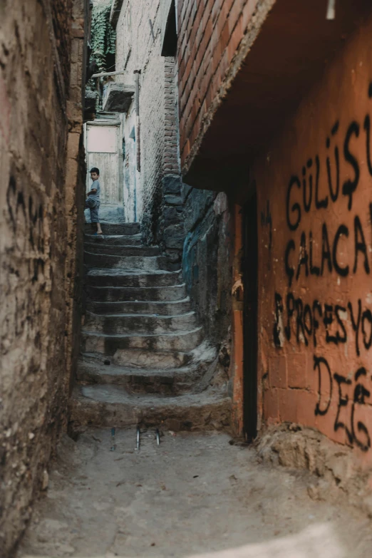 a narrow street has graffiti and stairs, graffiti is written on it