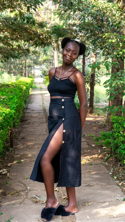 woman in a black outfit poses on a path