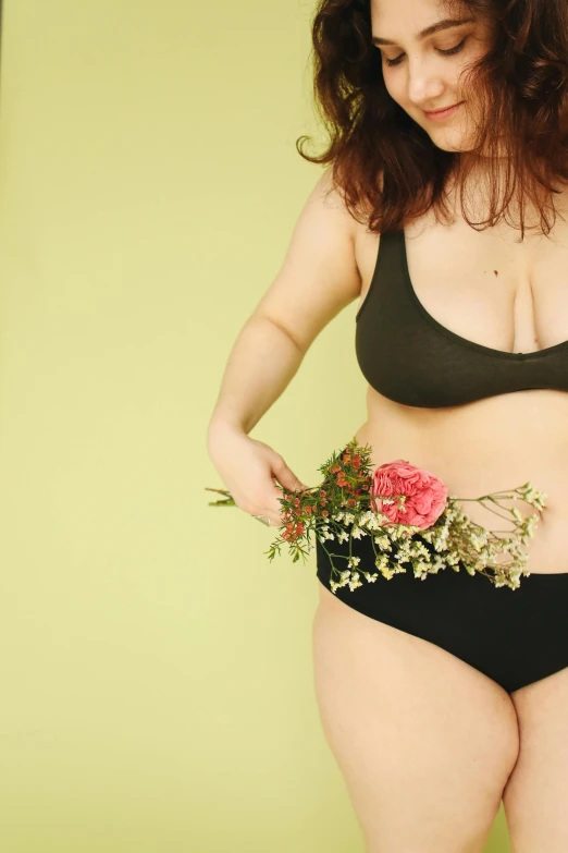 a woman is holding flowers while wearing a bikini