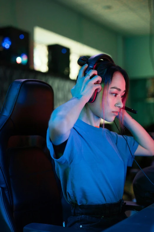 young woman in light blue outfit at computer desk with her head turned to the side