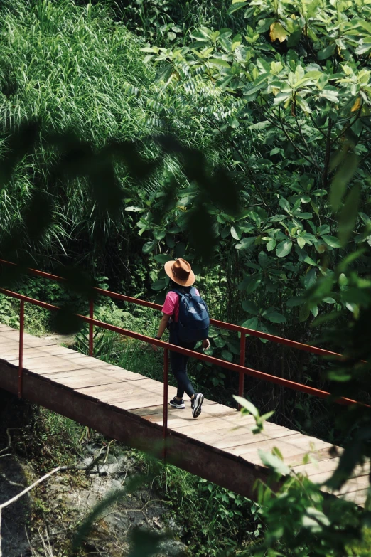 a man in a cowboy hat is crossing a bridge