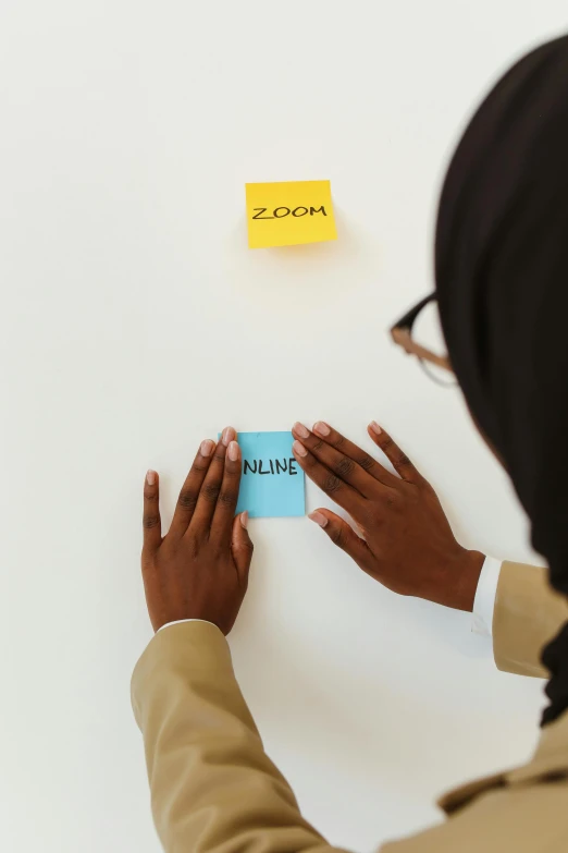 someone holding a blue piece of paper on top of a white wall