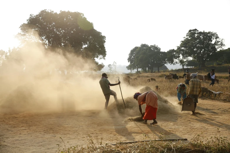 a group of people standing around a field with dust