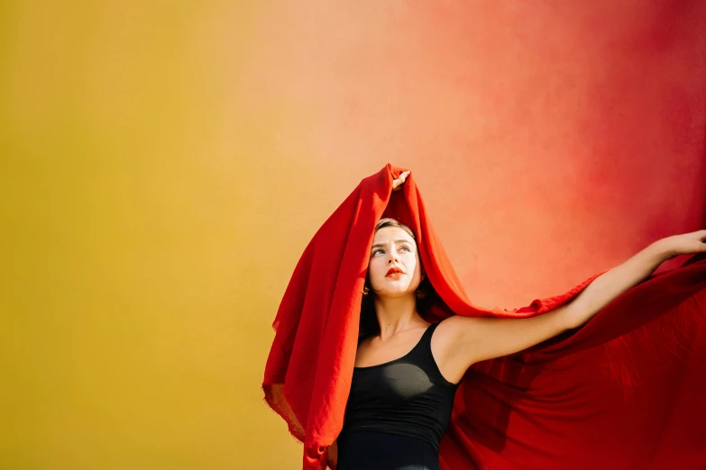 a woman in tight clothes holding a red sheet around her head