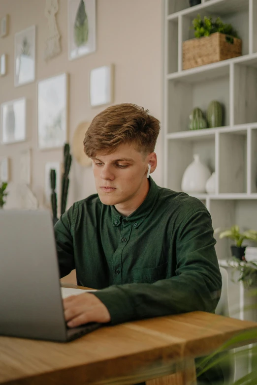 the man is working on his laptop while sitting at the table