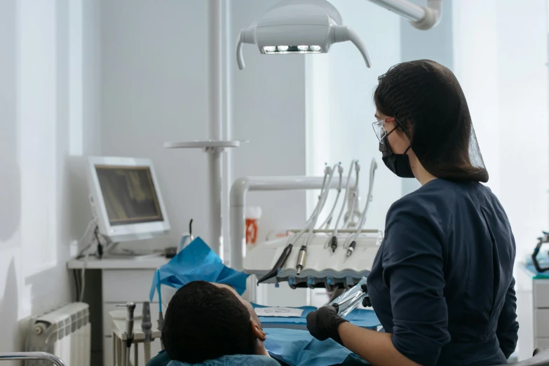 a dentist looks over his shoulder as a patient checks his teeth