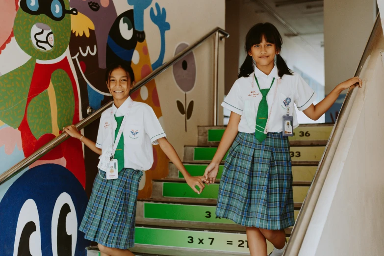 two children in school uniforms walking down stairs