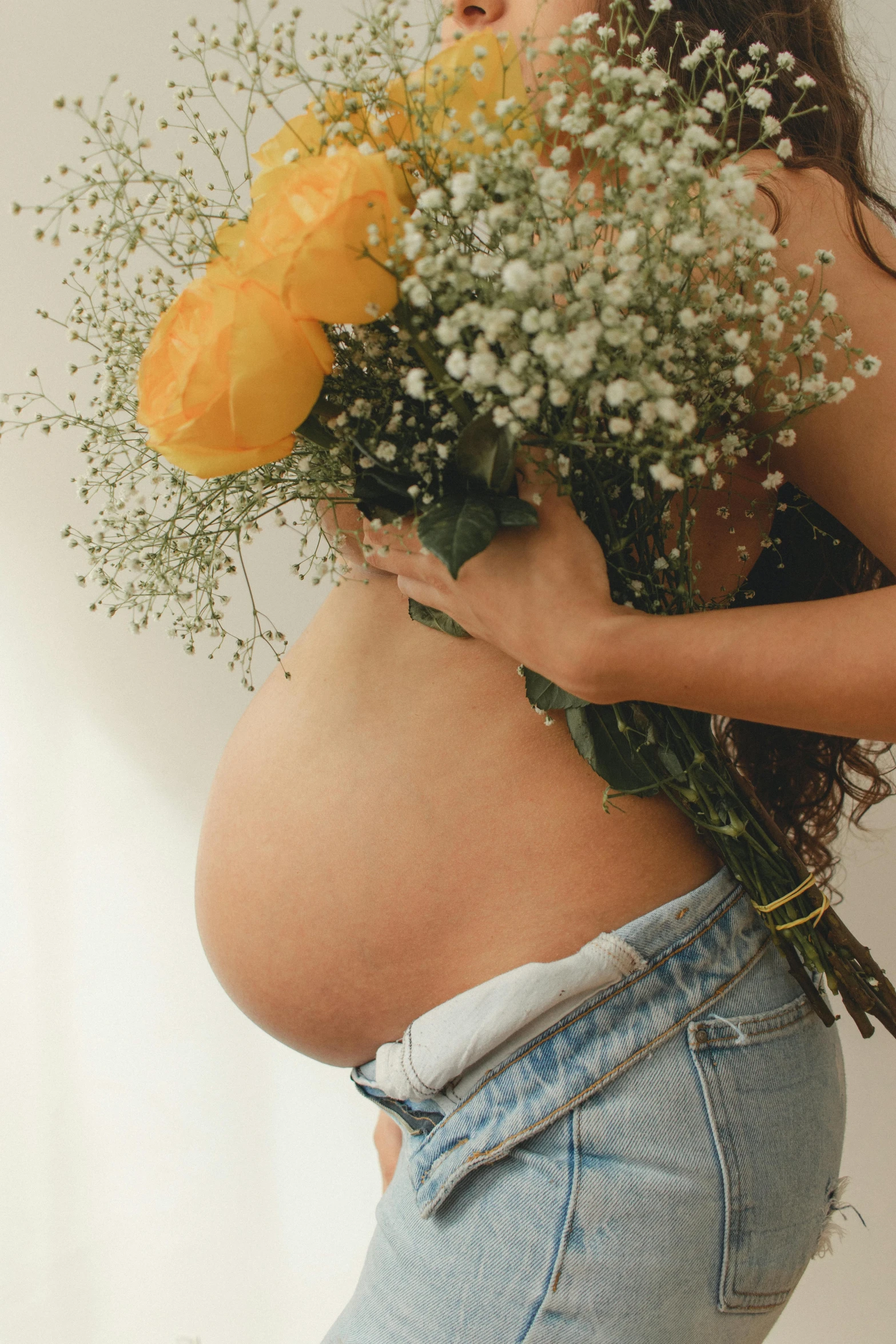 a pregnant belly with flowers in her hands