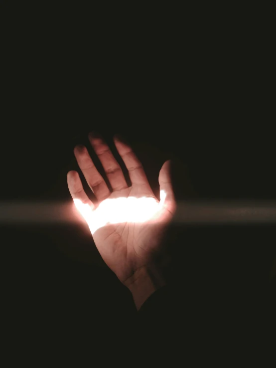 a hand holding a lit object over dark surface