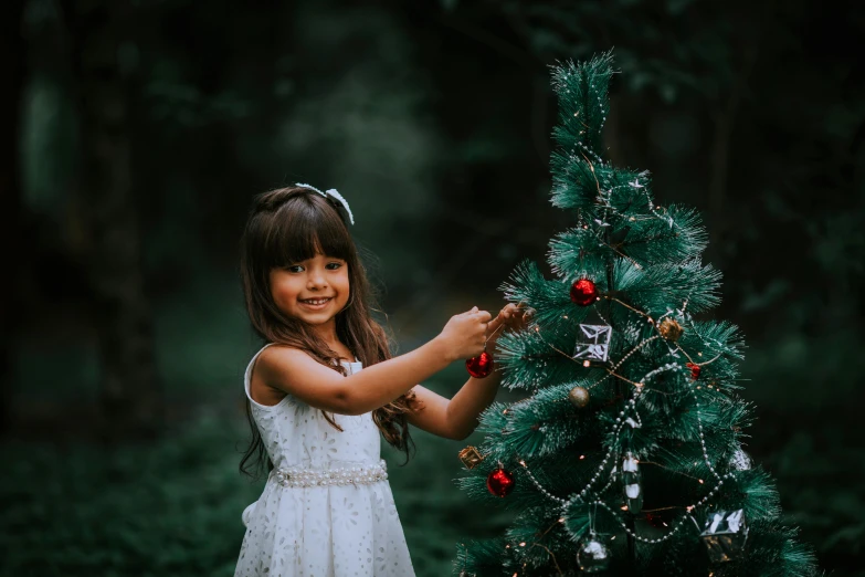 a little girl putting on a christmas tree
