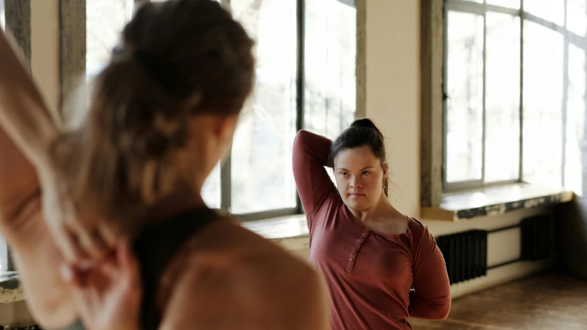 woman on mat doing yoga exercise with a pole in front of her