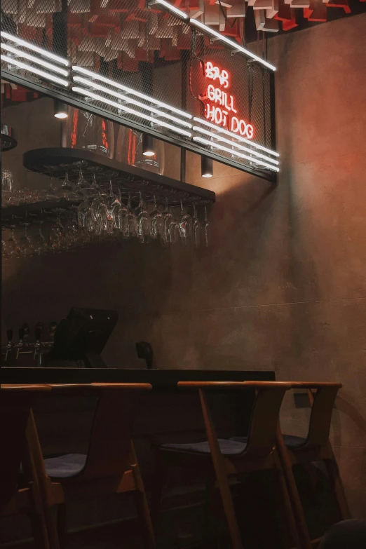 a dark lit bar has wooden chairs, and signs