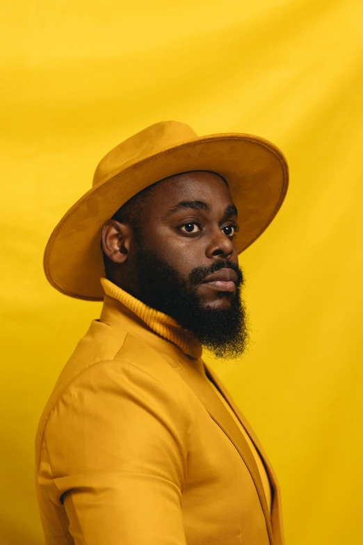 a man is standing in front of a yellow wall