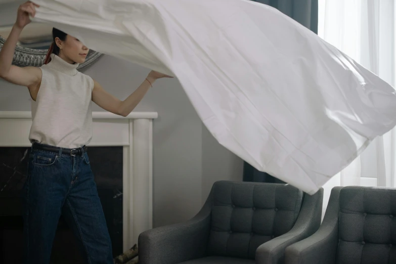 woman covering a white sheet in front of a couch