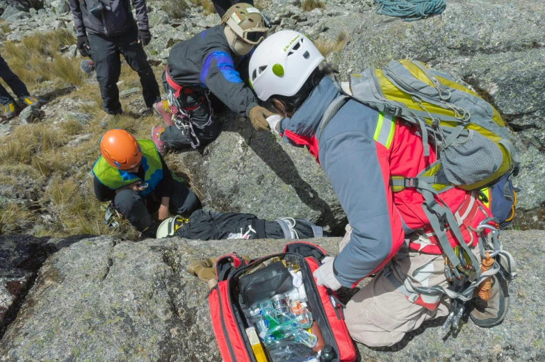 a person climbing up a rocky mountain with backpack and other people nearby