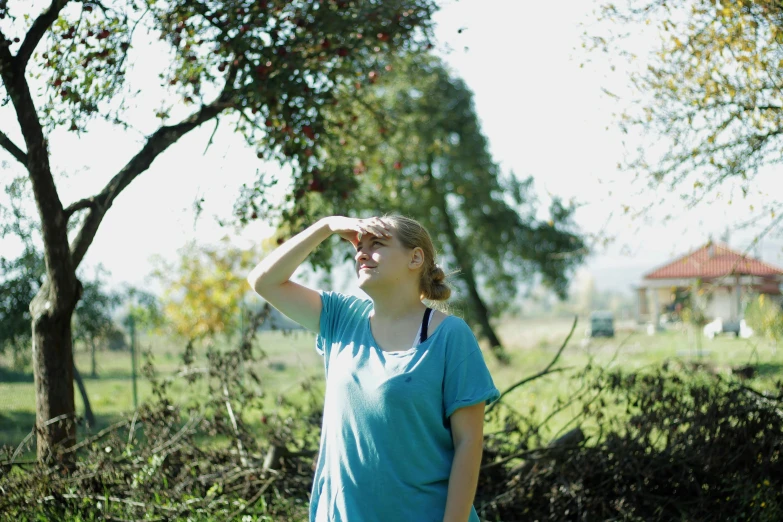 a woman is observing a bird under a tree