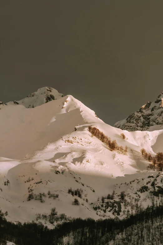 a large mountain covered in snow with a cloudy sky