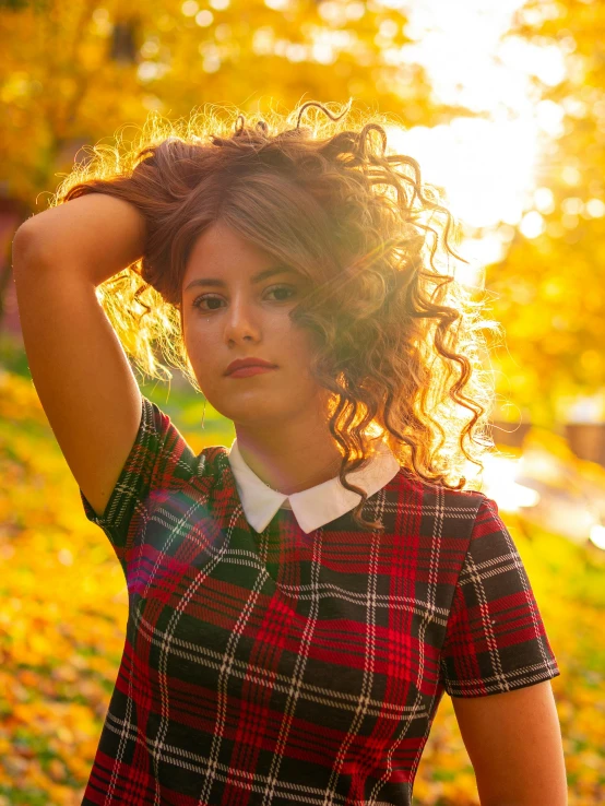 a woman poses in the fall leaves near a stream