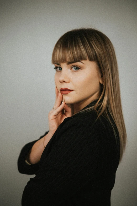 the woman is posing for a picture and holding her chin up