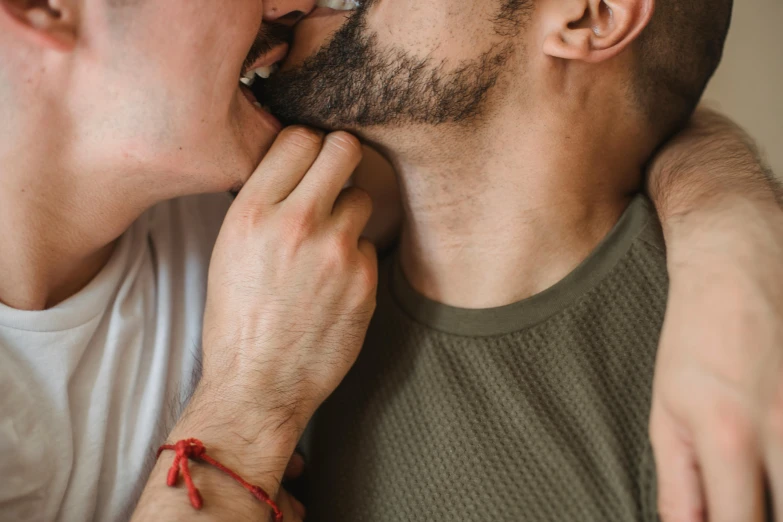 a man with a beard is touching a mans neck