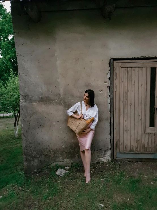 a woman leaning against a stone building wearing a skirt