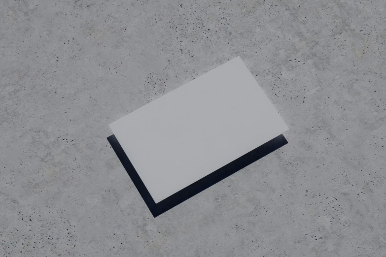 a square piece of paper laying on top of cement