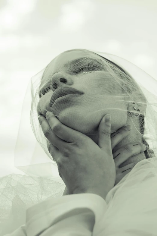 a black and white po of a woman covering her face with her veil