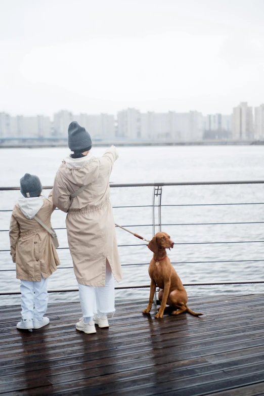 woman and child are walking with a dog on a dock