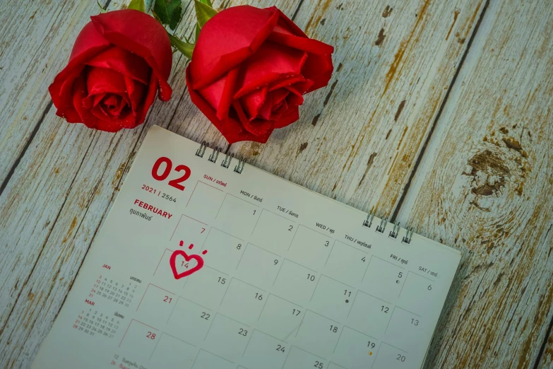 red roses are placed next to a calendar