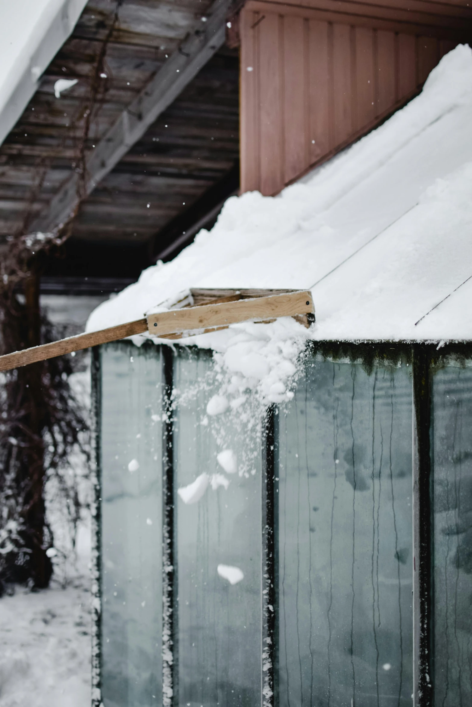 a view from behind a building shows snow clings and a broken door